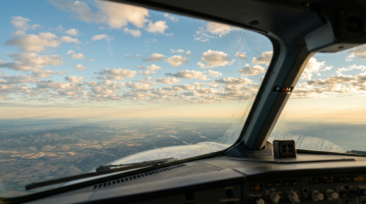 View through an airliner cockpit windscreen of fair-weather clouds at golden hour