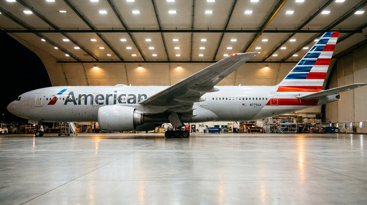 American Airlines Boeing 777-300ER in a maintenance hangar at night, side profile