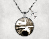 Thumbnail for Departing Aircraft & City Scene behind aviation necklace, stainless steel body with engraved detail.