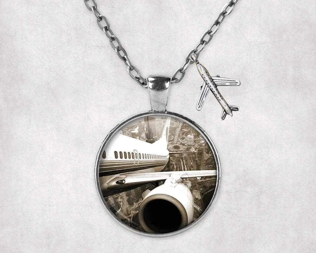 Departing Aircraft & City Scene behind aviation necklace, stainless steel body with engraved detail.